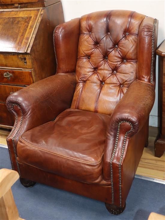 A modern buttoned leather wing armchair